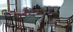 Un coin repas avec une table dressée pour quatre personnes, entourée de chaises en bois dotées de coussins blancs.