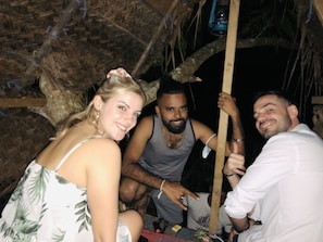 A group of people in a rustic, thatched-roof structure.