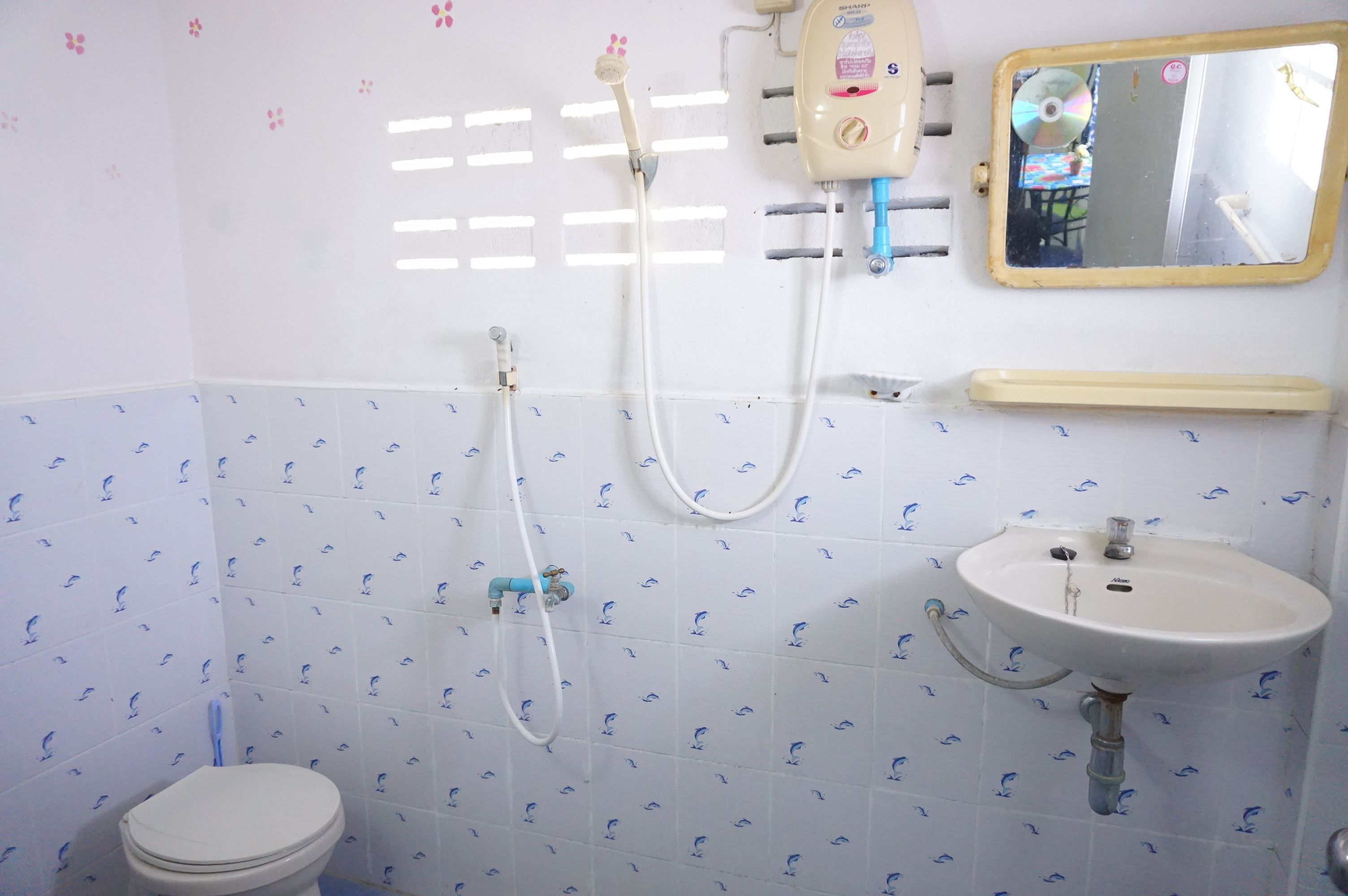 Un baño con inodoro, lavamanos, ducha con cabezal de ducha de mano y espejo.