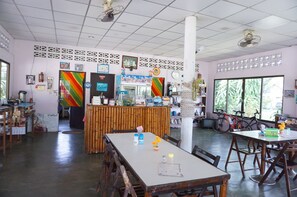 A spacious room with a large window, a reception desk, and several tables and chairs.