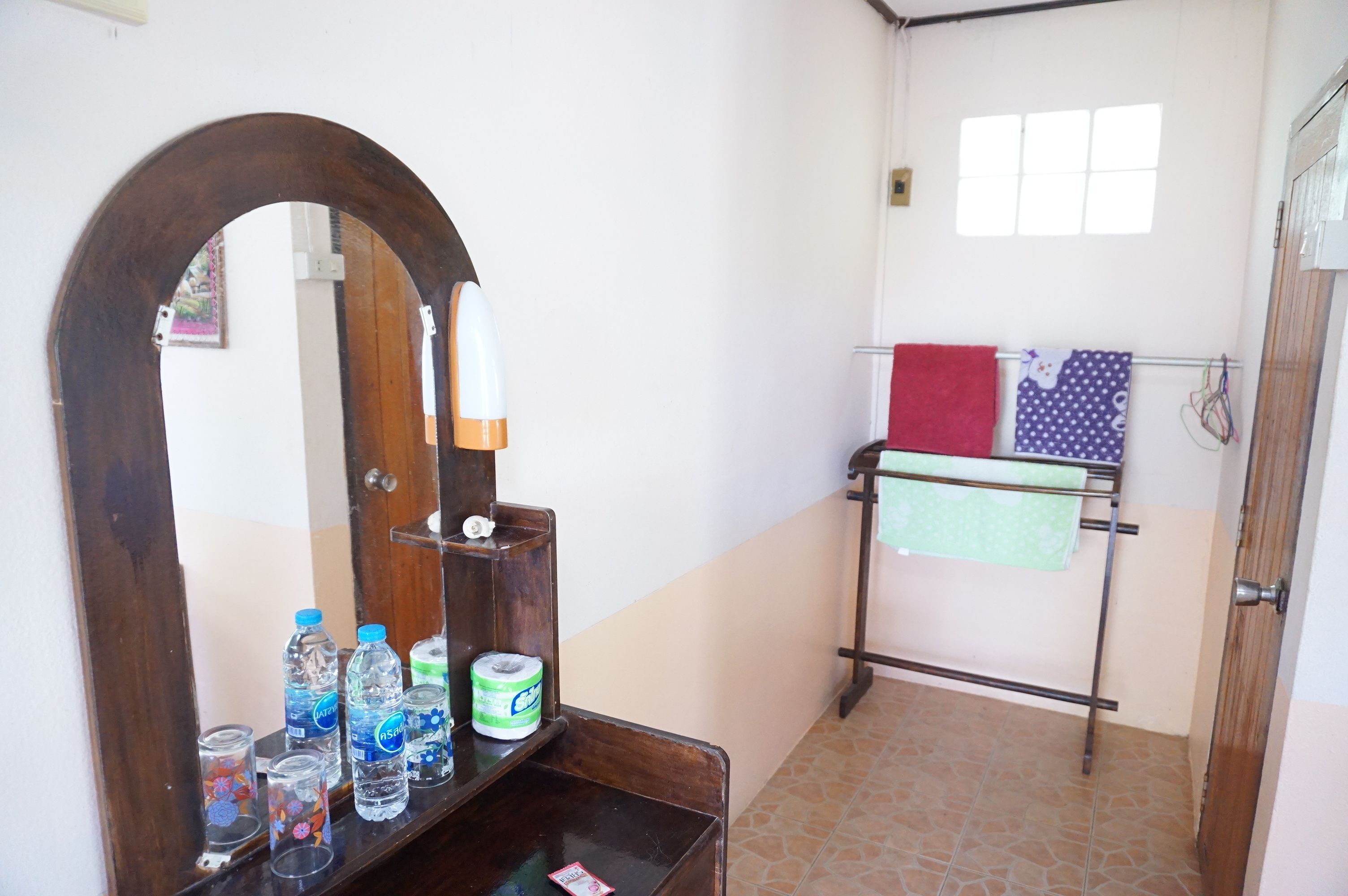 Un baño con tocador de madera, espejo y perchero con varias toallas.