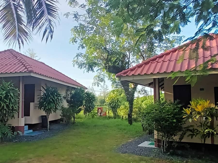 Two buildings with red roofs, surrounded by lush greenery and trees.