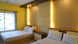 Una habitación de hotel con dos camas, una ventana con cortinas y una pared con diseño.
