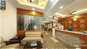 A hotel lobby with a reception desk, seating area, and a clock on the wall. - Kgees- HillTown Hotel (Idukki)