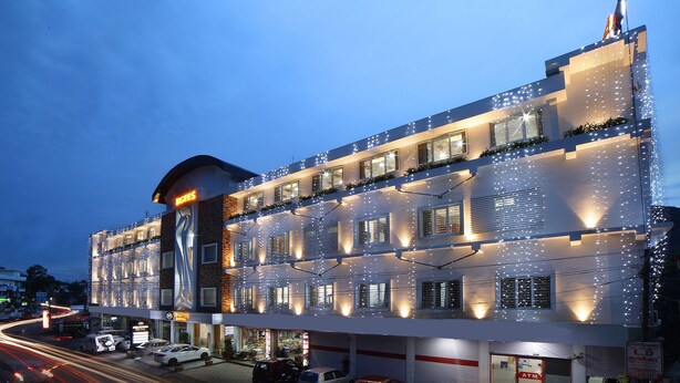 A multi-story hotel with a modern facade, multiple balconies, and a prominent entrance. - Kgees- HillTown Hotel (Idukki)