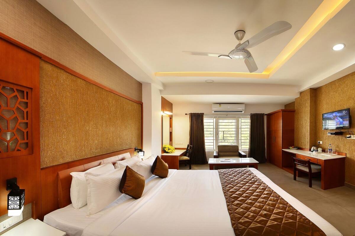 A hotel room with a bed, desk, TV, and ceiling fan.