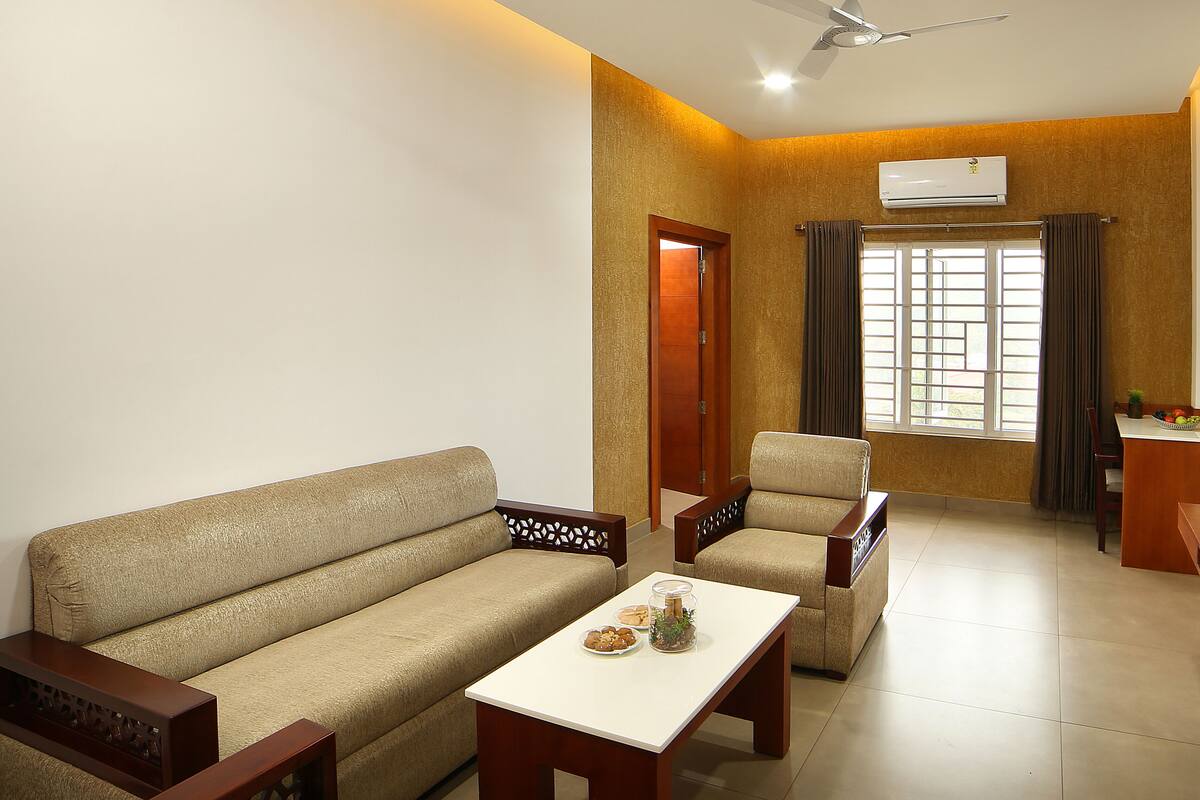 A living room with a sofa, armchair, coffee table, and a ceiling fan.