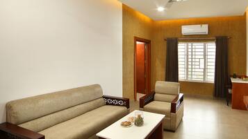 A living room with a sofa, armchair, coffee table, and a ceiling fan.