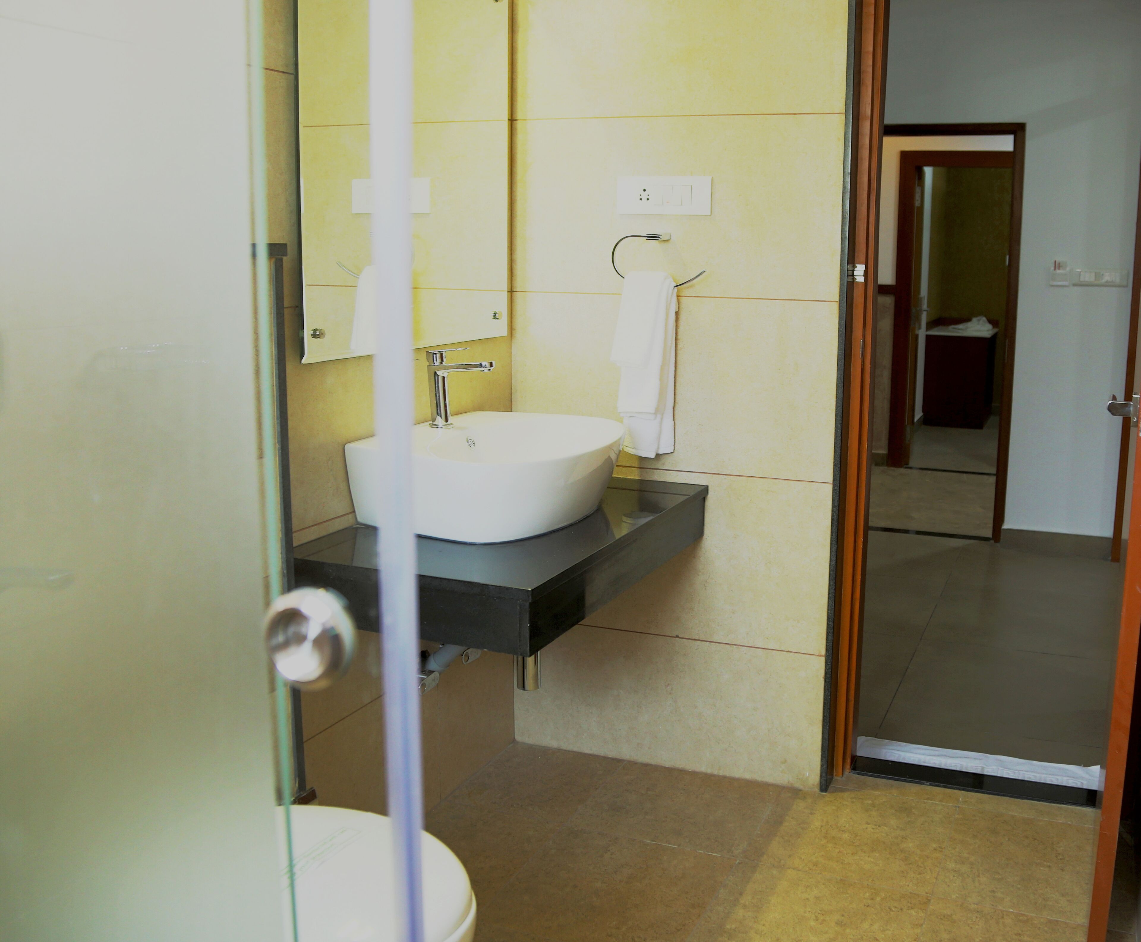 Un baño con un lavamanos blanco, un espejo y una toalla colgada en la pared.
