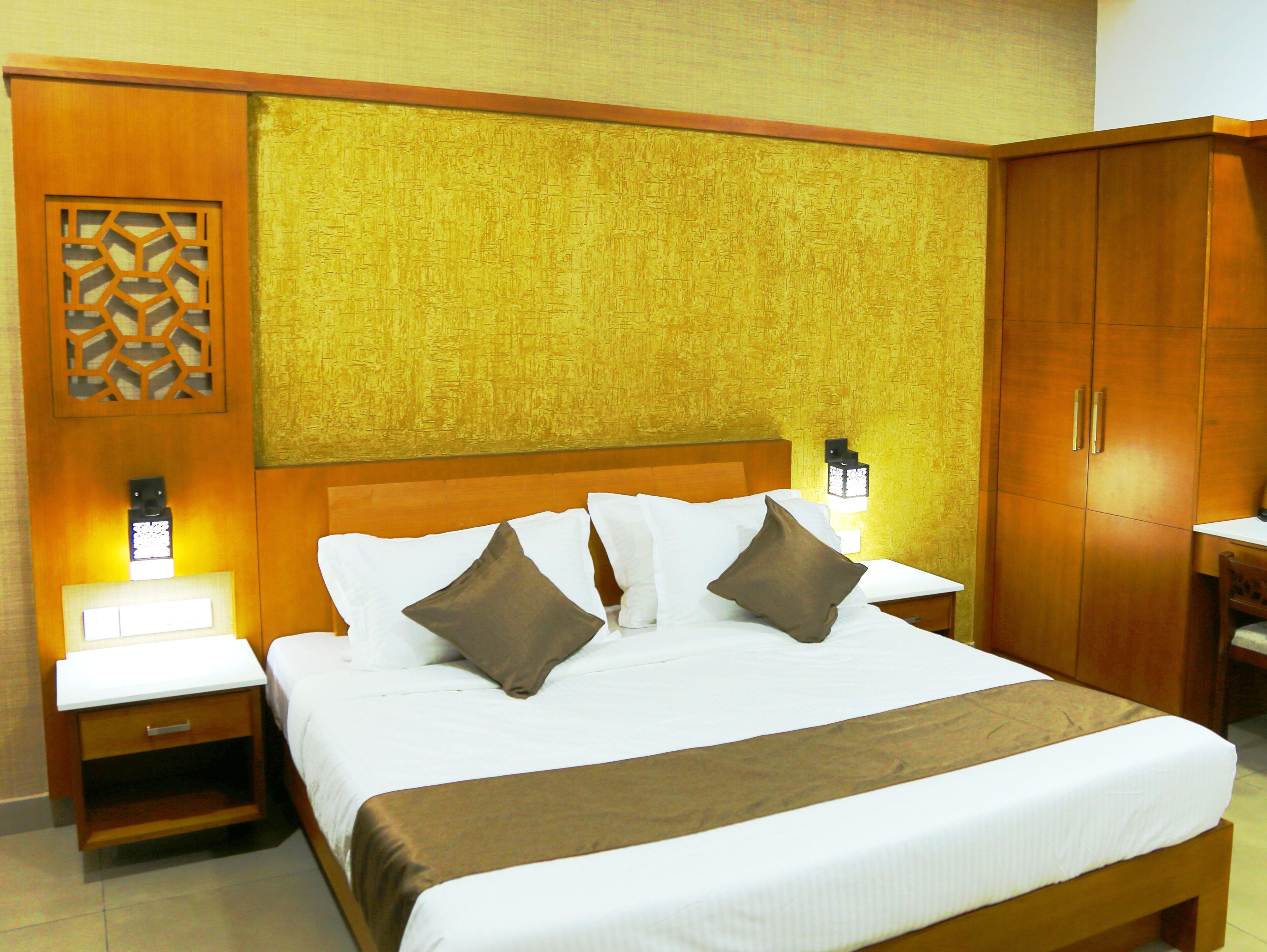 A neatly made bed with white and brown bedding, wooden headboard, and bedside lamps.
