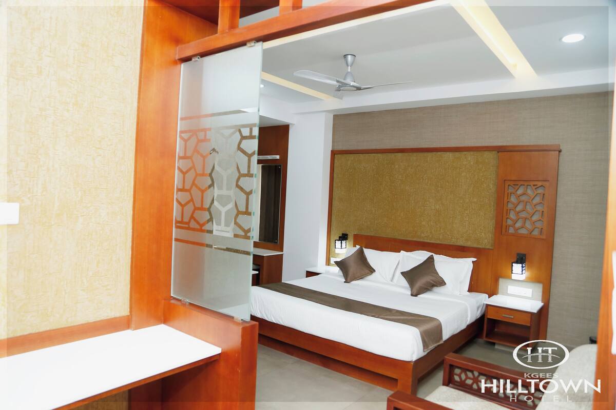 A hotel room with a large bed, wooden headboard, bedside tables, and a ceiling fan.