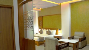 A hotel room with a bed, two bedside tables, a chair, and a desk. - Kgees- HillTown Hotel (Idukki)