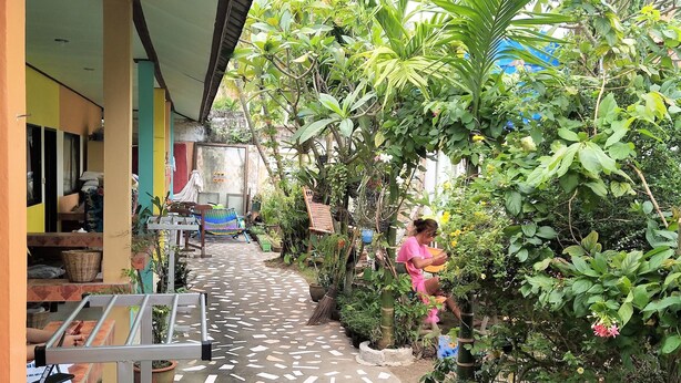A covered walkway with a tiled floor, surrounded by potted plants and greenery. - Casamarina Guest House (Ko Chang)