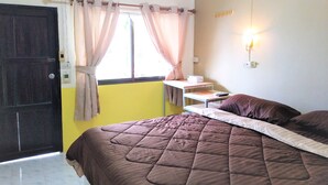 A room with a bed, a desk, a window with curtains, and a wall-mounted light. - Casamarina Guest House (Ko Chang)
