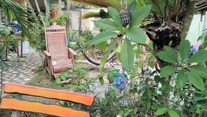 A patio area with wooden benches and tables, surrounded by various potted plants and a hammock. - Casamarina Guest House (Ko Chang)