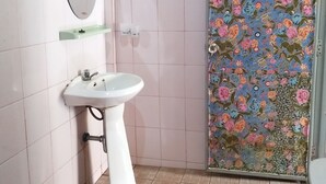A bathroom with a white sink, a mirror, and a shower with floral tiles. - Casamarina Guest House (Ko Chang)