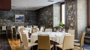 A dining area with round tables, chairs, and a stone wall.