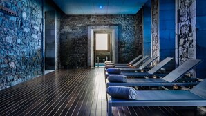 Un cuarto de spa con paredes de piedra, piso de madera y camastros con toallas.