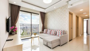A modern living room with a sofa, a TV, and a balcony with curtains. - Spacious Saigon (Ho Chi Minh City)