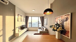 A modern dining area with a wooden table, chairs, a pendant light, and artwork on the walls. - Spacious Saigon (Ho Chi Minh City)