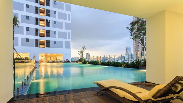A rooftop pool with lounge chairs, a city skyline view, and a modern building in the background. - Spacious Saigon (Ho Chi Minh City)