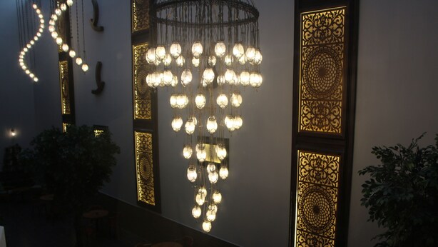 A modern interior with a unique chandelier design, patterned wall panels, and potted plants. - Hotel Minerva Pazar (Pazar)