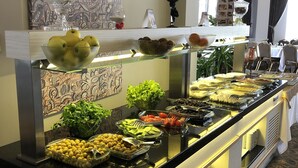 A buffet with various food items, a decorative wall, and a patterned carpet. - Hotel Minerva Pazar (Pazar)