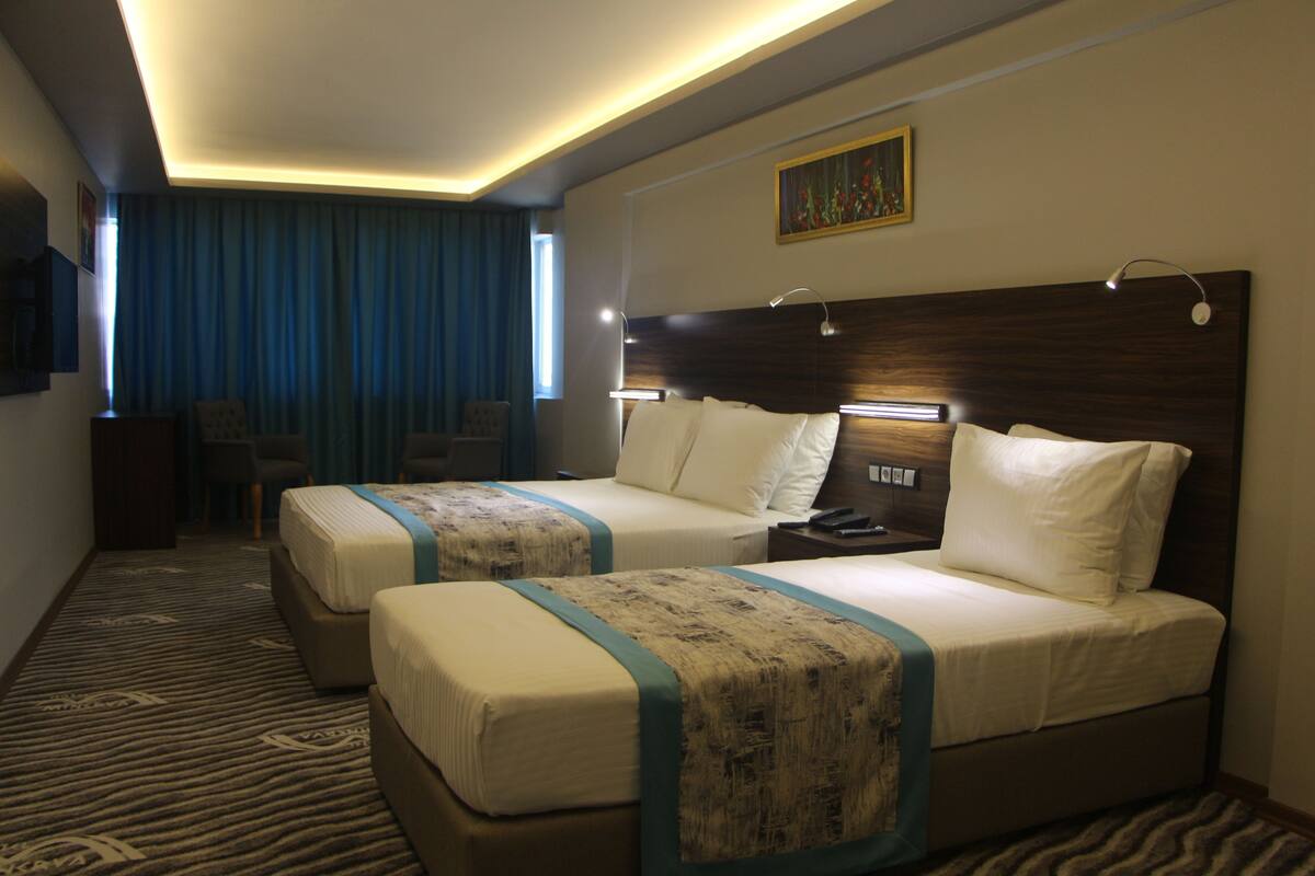A hotel room with two beds, a desk, and a chair.