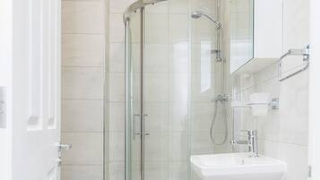A modern bathroom with a glass-enclosed shower, a white sink, and a mirror above it.