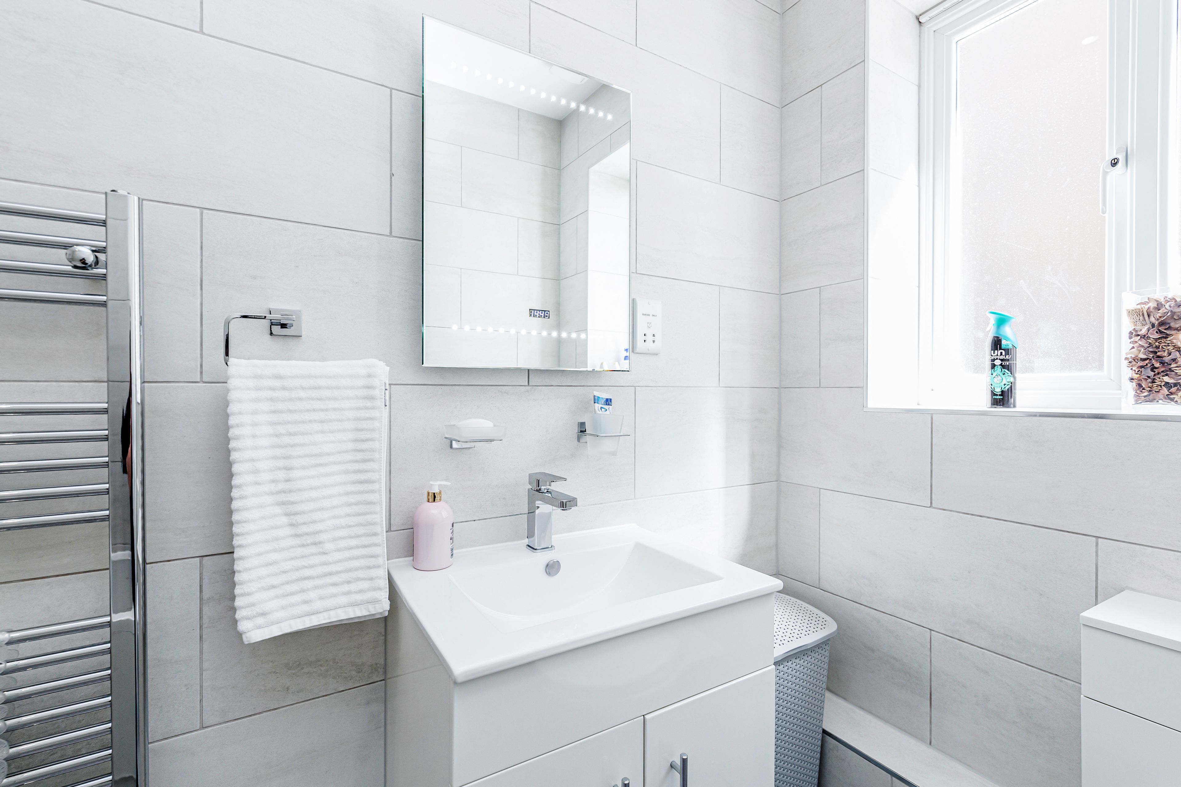 A modern bathroom with a white sink, mirror, and towel rack.