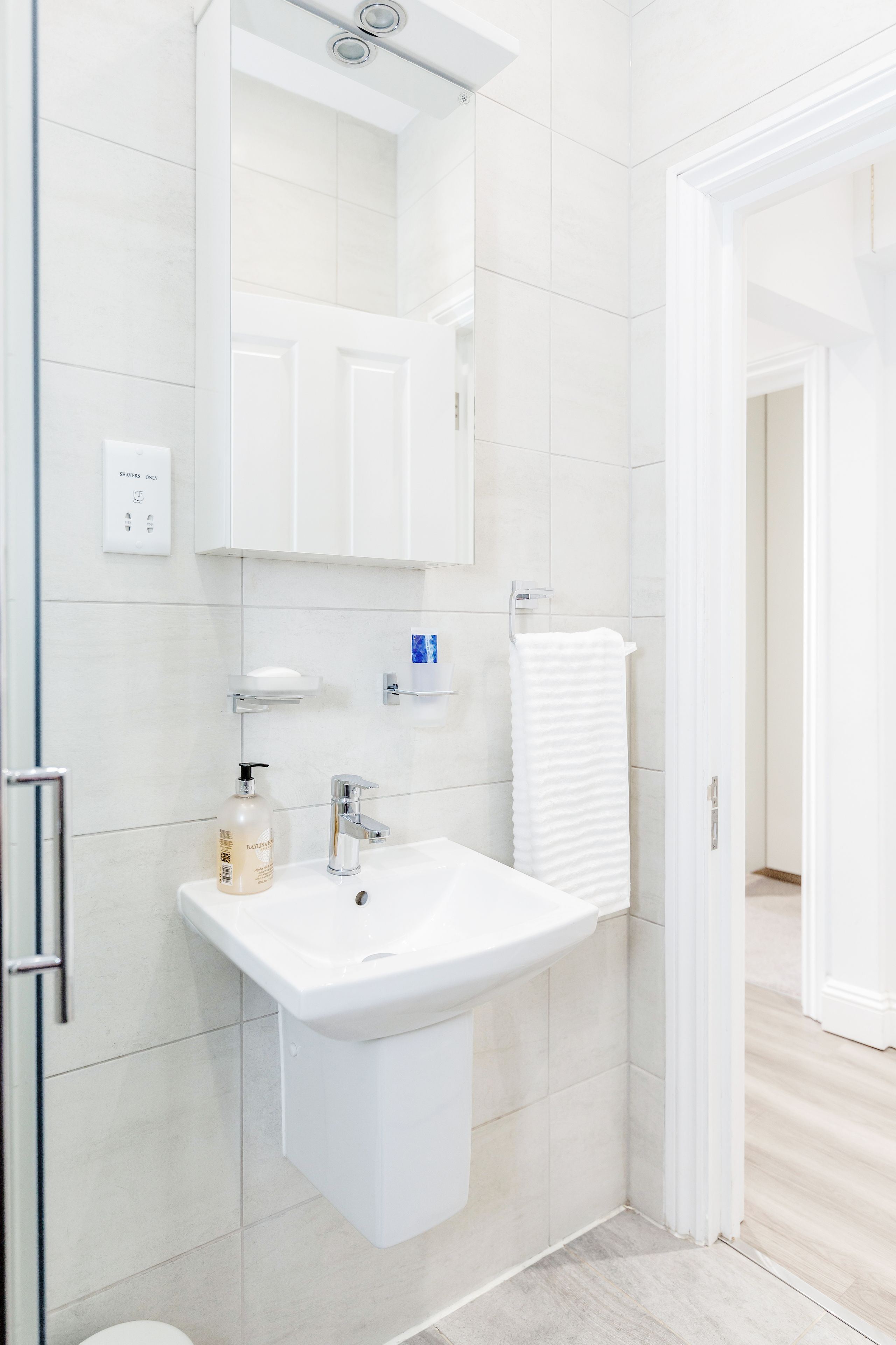 A modern bathroom with a white sink, mirror, and towel rack.