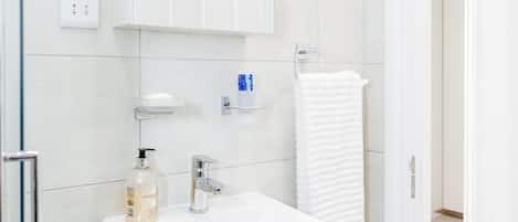 A modern bathroom with a white sink, mirror, and towel rack.