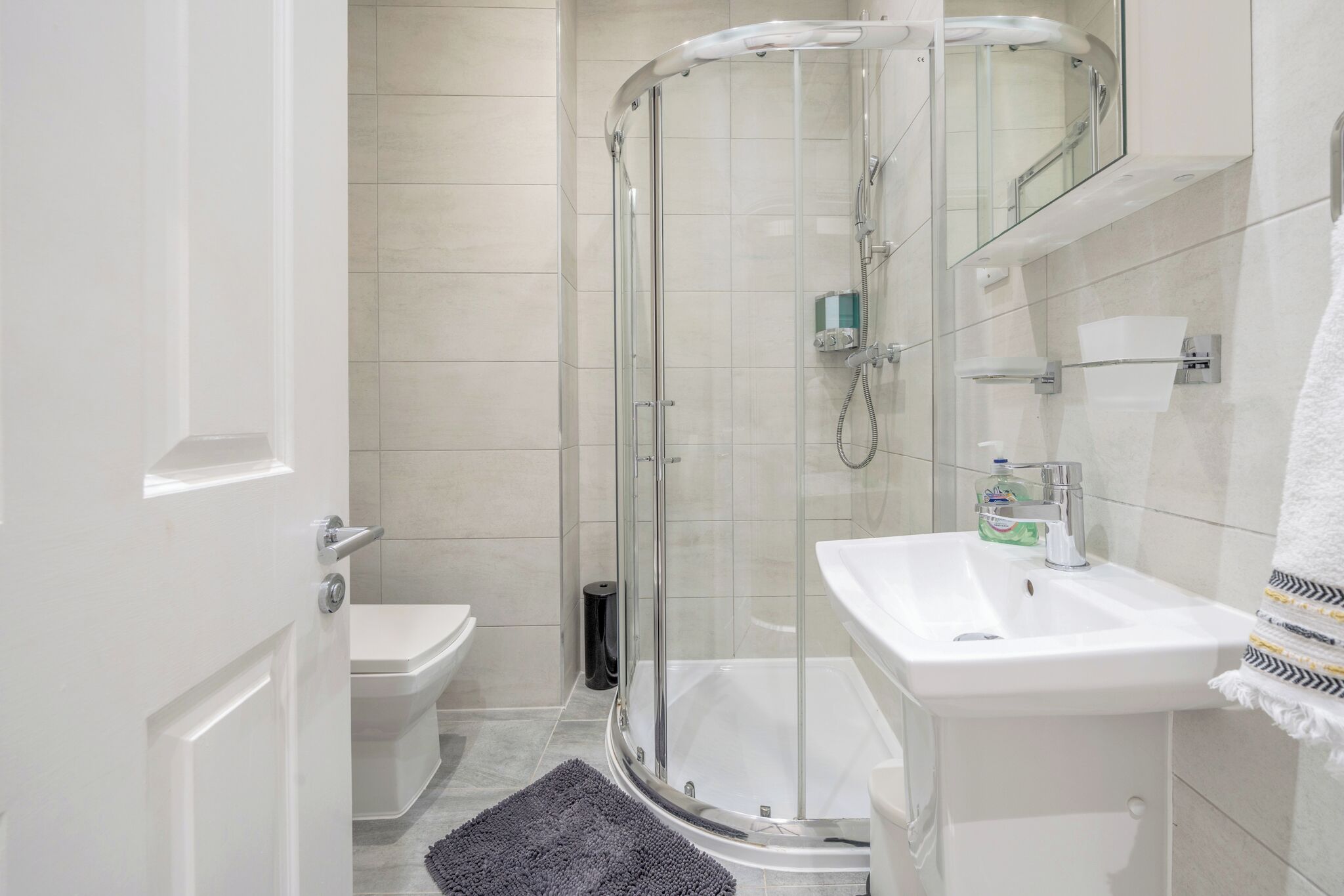 A modern bathroom with a glass-enclosed shower, a white sink, and a toilet.