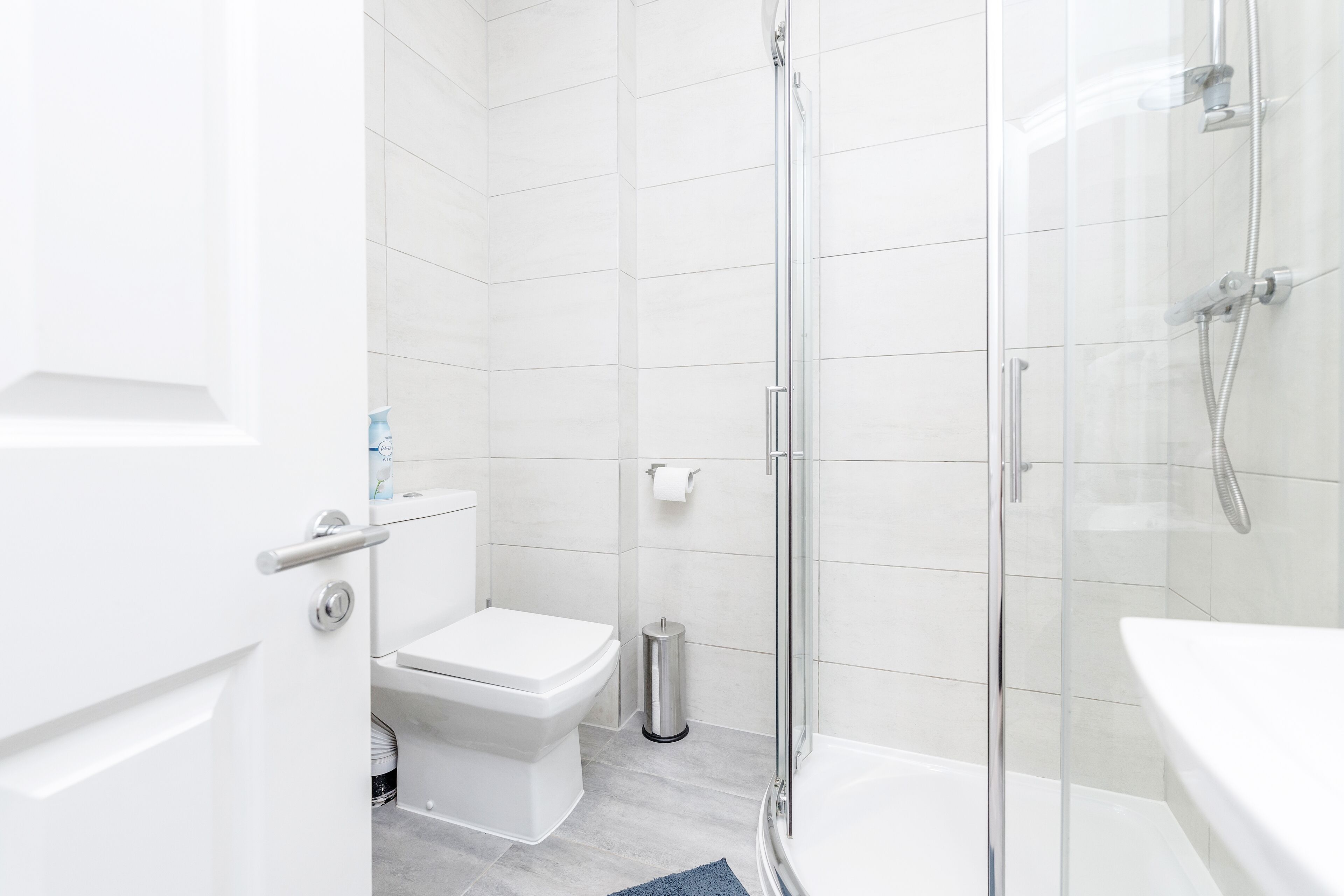 A modern bathroom with a toilet, shower, and sink.