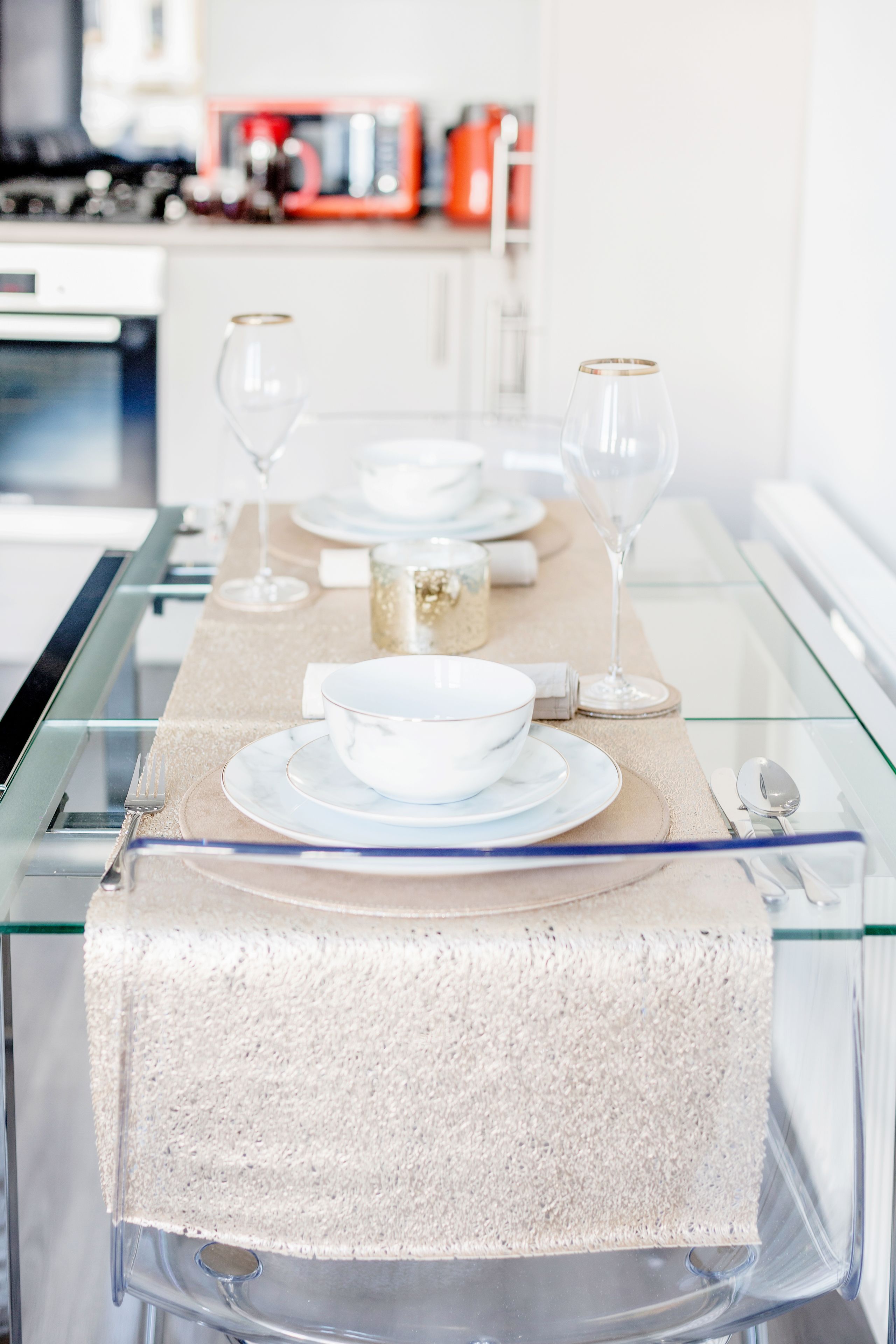 Una cocina moderna con una mesa de vidrio dispuesta para una comida.