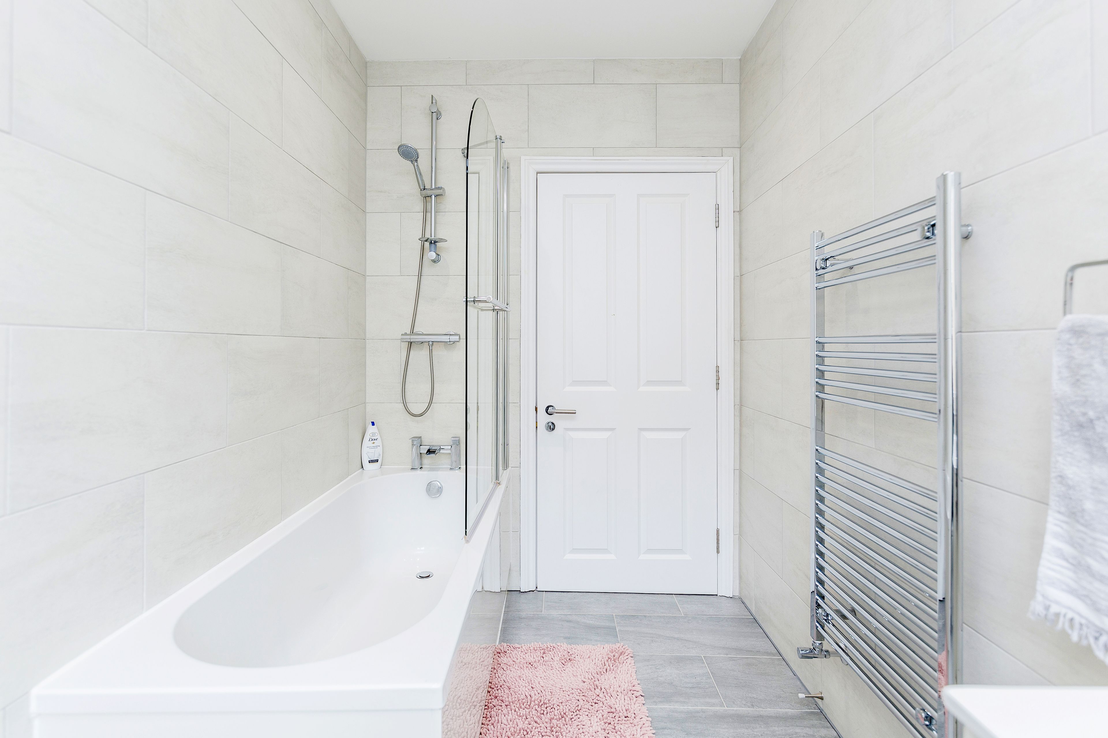 Une salle de bain avec une baignoire blanche, une douche et un porte-serviettes.