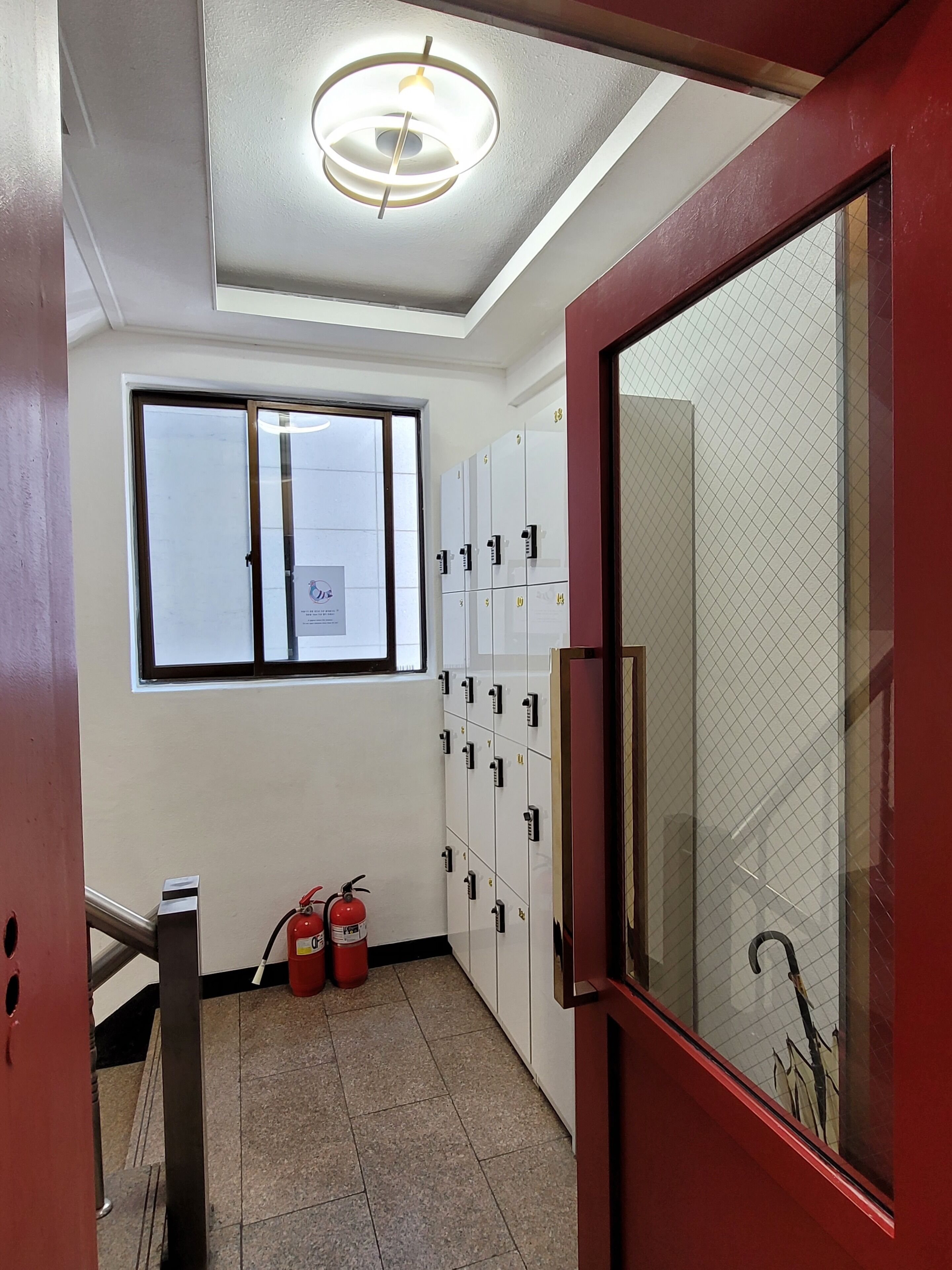 Um corredor com armários, um extintor de incêndio e uma janela.