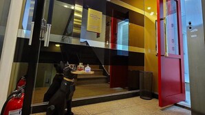 A modern hotel lobby with a glass wall, a red door, and a fire extinguisher on the floor. - LotteTower Rainbow House (Seoul)