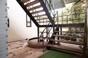 A staircase leading to a rooftop garden with a water feature and a stone wall. - OYO 674 Greenery Home (Ranong)