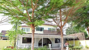 A two-story building with a covered patio area, surrounded by greenery and trees. - OYO 674 Greenery Home (Ranong)