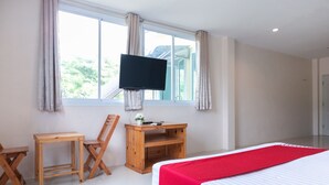 A bedroom with a bed, a desk, a chair, and a TV mounted on the wall. - OYO 674 Greenery Home (Ranong)