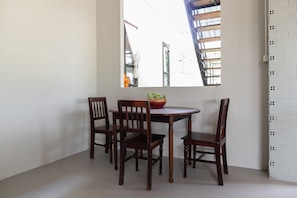 Een eethoek met een ronde tafel en vier houten stoelen. Op tafel staat een schaal met een plant.