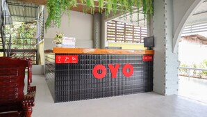 A reception desk with the name "OYO" prominently displayed, surrounded by hanging plants and a modern interior design. - OYO 674 Greenery Home (Ranong)