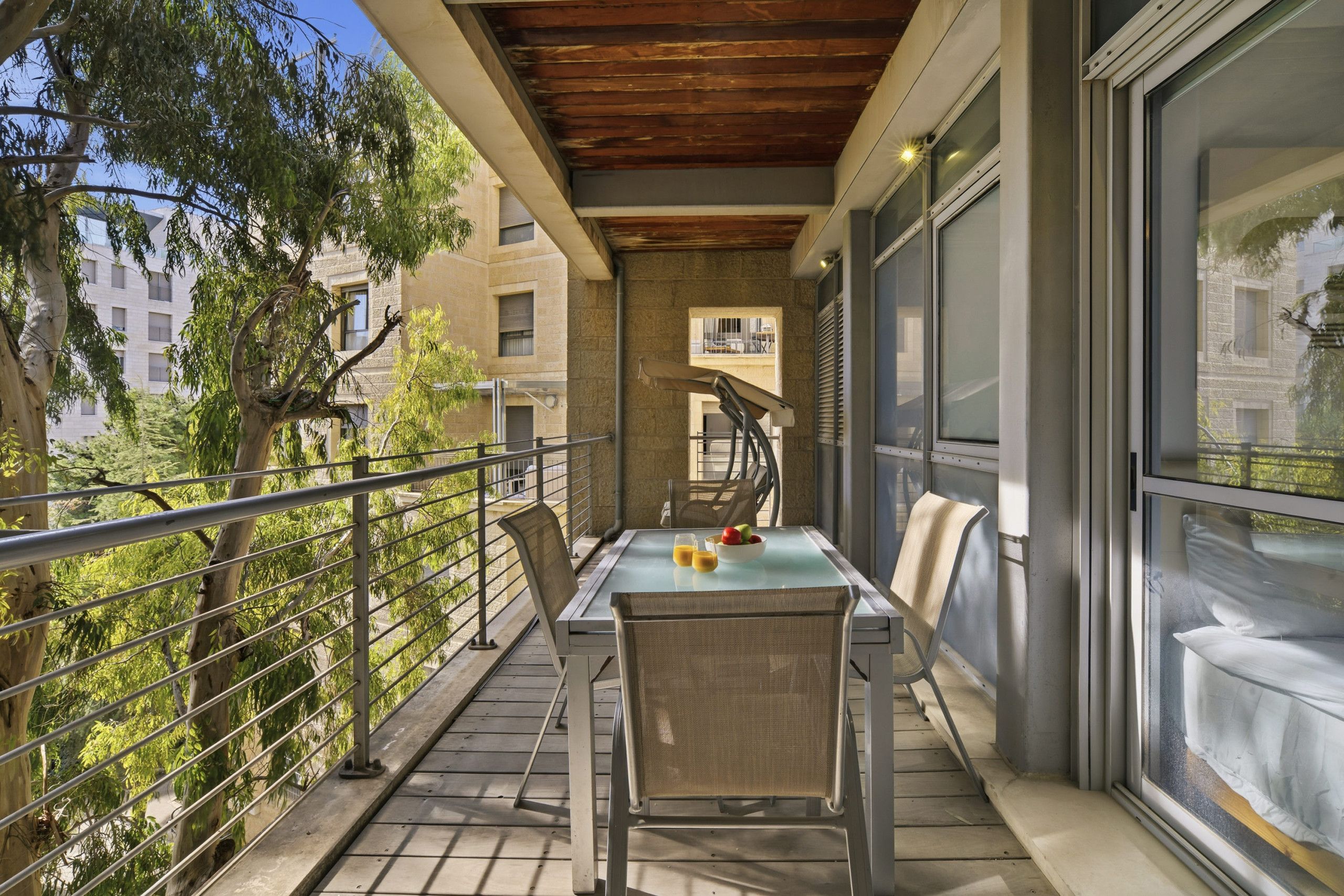 A balcony with a table and chairs, a railing, and a view of buildings and trees.