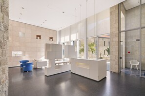Un lobby moderno con mostrador de recepción, zona de estar y ventanas amplias.