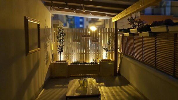 A narrow corridor with a wooden table and chairs, a decorative fence, and a window on the right. - Panta Rei B&B (Salerno)