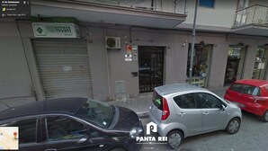 A street view with parked cars, a closed shop with a sign reading "NO CASA," and a visible "PANTA REI" sign. - Panta Rei B&B (Salerno)