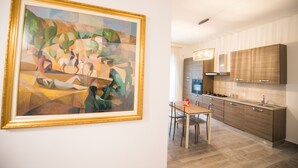 A modern kitchen with wooden cabinets, a dining table with chairs, and a large abstract painting on the wall. - Panta Rei B&B (Salerno)
