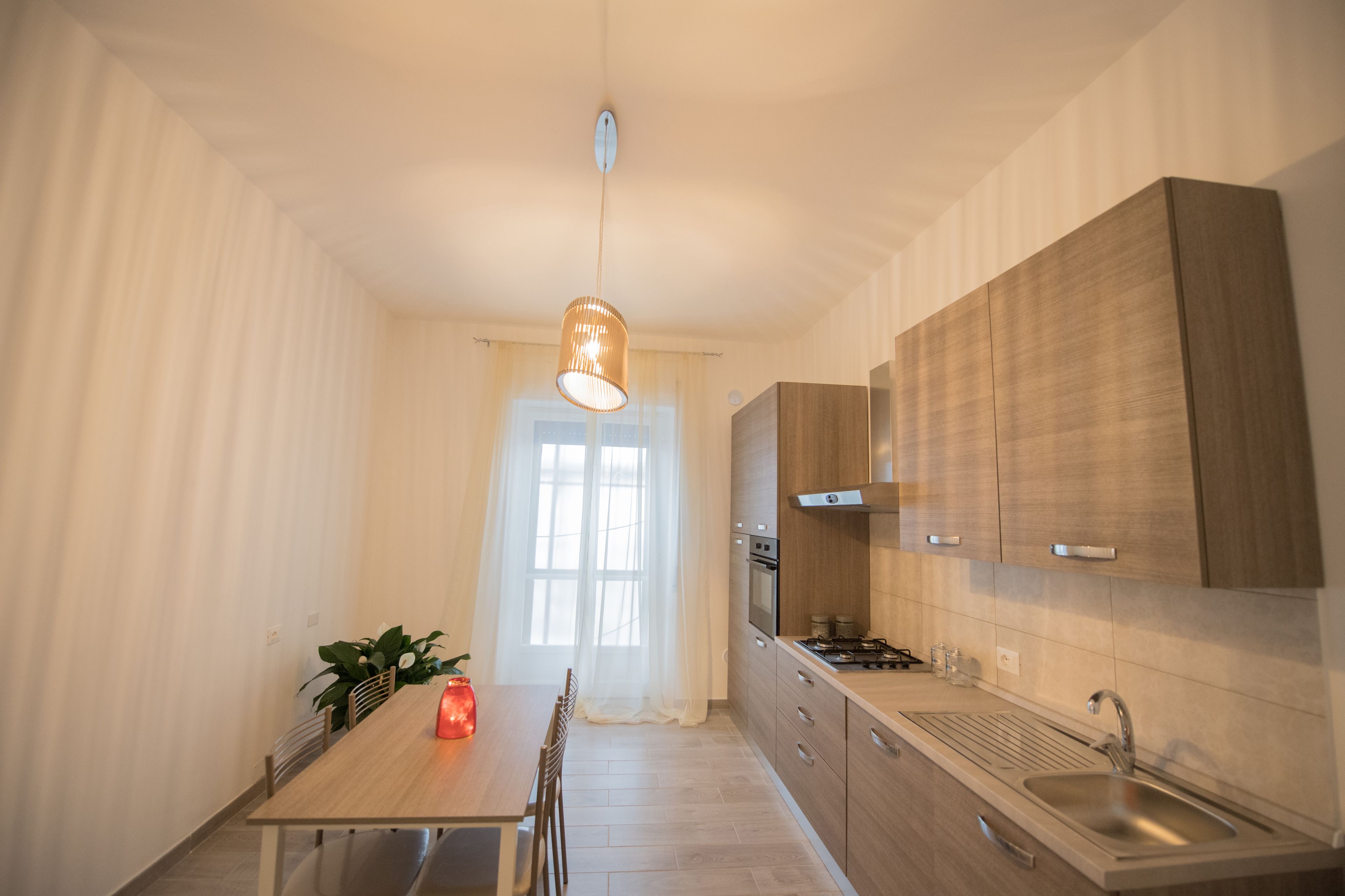 Eine moderne Küche mit Holzschränken, einer Edelstahlspüle und einem Essbereich mit Tisch und Stühlen.