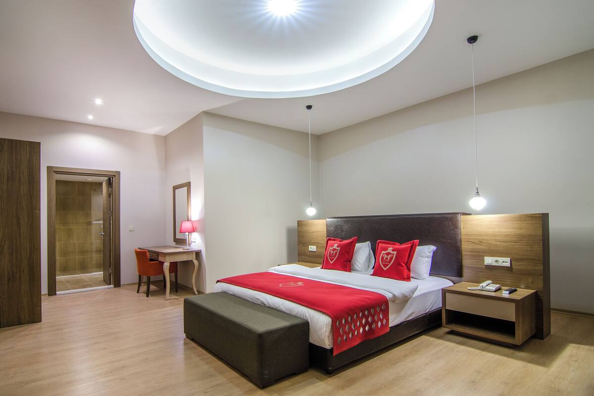 Una habitación de hotel moderna con una cama grande, una mesita de noche y un escritorio con una silla.
